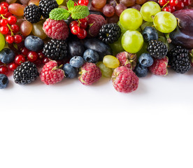 Mix berries and fruits on a white background. Fresh raspberries, red currants, blackberries, blueberries, grapes with mint leaves on white background. Top view. Fruits with copy space for text. 