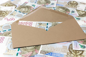 Banknoty 500 PLN w brązowej kopercie na tle z banknotów