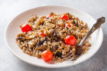Buckwheat porridge with mushrooms and cherry tomatoes on a plate.