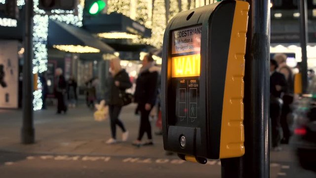 Pedestrian pushes button and waits for the green sign at a crossing