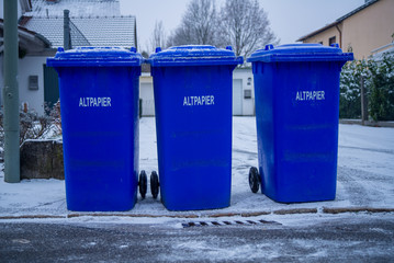 Waste paper bins stand at a curbside after collection