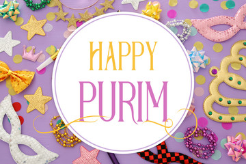 Purim celebration concept (jewish carnival holiday) with masks and colorful party accessories over pink, purple wooden background. Top view.