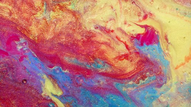 Colorful sparkling paints mix in beautiful patterns. Oil ink of red, yellow, blue and other colors spread on the surface and mix one into another creating amazing textures and design.