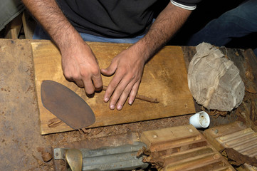 Close up of hands making a cigar from tobacco leaves