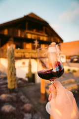 Point-of-View-Shot of a hand holding a glass of red wine into the sun