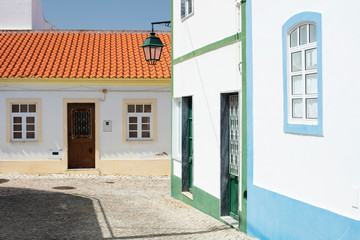 street in portuguese city with colored roof and street lighter under blue sky
