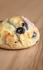 Bun with raisins on a wooden table.