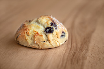 Bun with raisins on a wooden table.