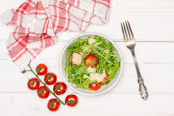 Finished step. ready to eat. recipe step by step arugula salad in a grey ceramic bowl flatlay on white wood