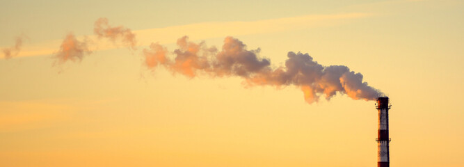 Photo of factory pipe with smoke at sunset