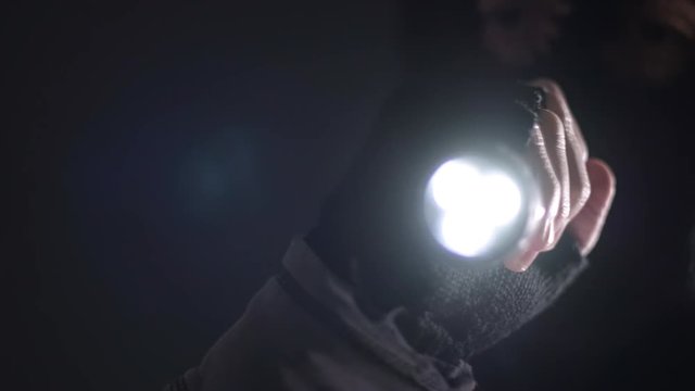 Burglar intruder with flashlight torch at night, low key selective focus