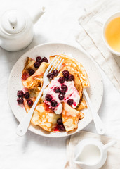 Crepes with cherry sauce and cream on a light background, top view. Delicious breakfast, dessert