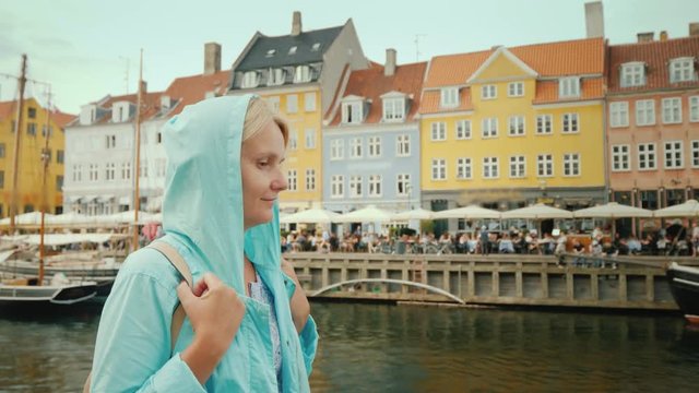 Side view of A woman strolls along the Nyhavn canal, against the background of famous colorful houses. The most popular place among tourists is in Copenhagen, Denmark