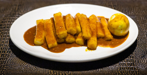 Tteok bokki on white plate on leathed board