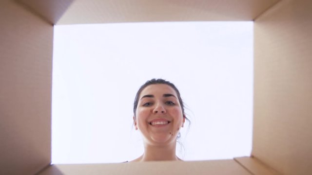delivery, mail and shipping concept - happy woman opening parcel or gift box and looking inside