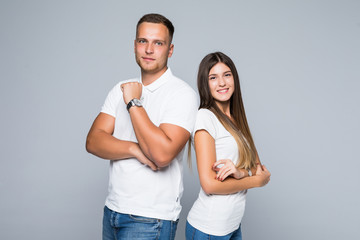 Attractive young couple standing back to back with arms crossed isolated on gray background