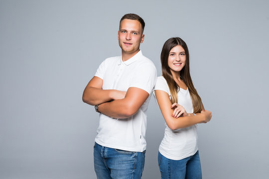 Portrait Of Couple Standing Back To Back And Looking At Camera Over Gray Wall