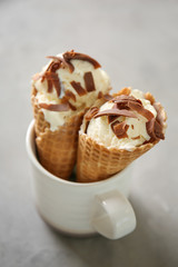 Waffle cones with delicious ice cream in cup on grey table