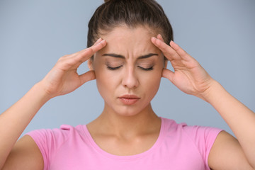 Woman suffering from headache on color background