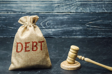 A bag of money and the word Debt and the hammer of the judge. Payment of taxes and of debt to the...