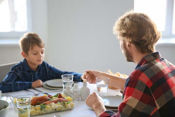 Father with son praying before meal at home
