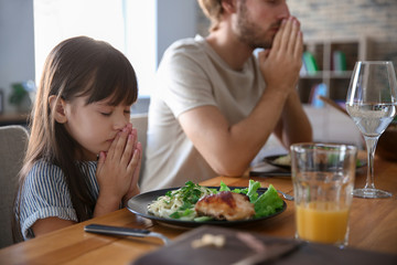 Family praying before meal at home