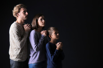 Praying family on dark background