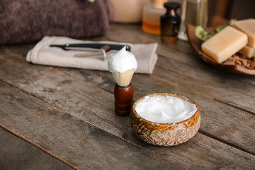 Shaving brush and bowl with foam on wooden table