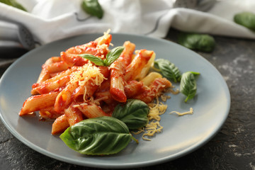 Plate with tasty penne pasta on grey table