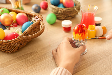 Woman painting Easter eggs on table
