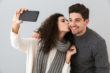 Photo of lovely man and woman taking selfie photo on smartphone, isolated over gray background
