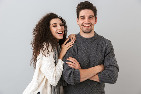 Portrait of satisfied couple man and woman smiling while hugging together, isolated over gray background