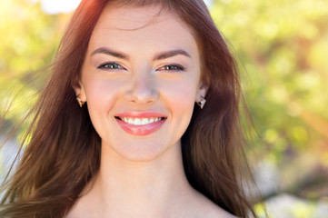 Fototapeta premium Beauty face of a young smiling woman outdoors.