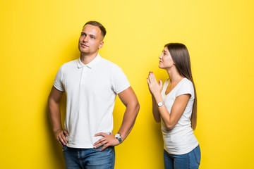 Young pretty woman apologizes to a man on the yellow background