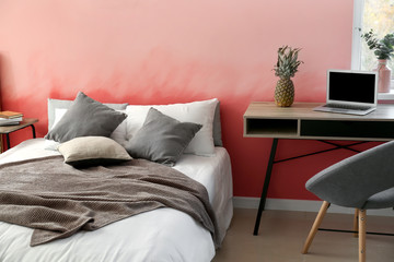 Interior of room with comfortable bed near pink wall