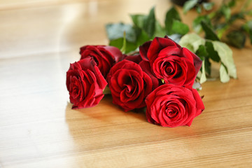 Bouquet of beautiful red roses on wooden table