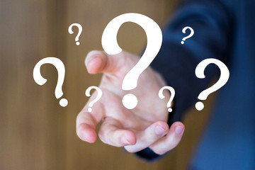 Businessman on blurred background using question marks icon.