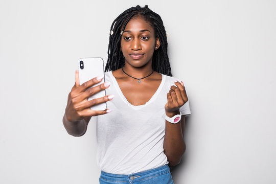 Young African American woman taking a selfie isolated on gray background