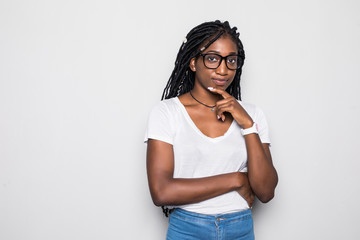 Portrait of beautiful casually dressed young afro american woman in round glasses having doubtful expression, looking away in indecisiveness, holding her chin, trying to find best solution. - obrazy, fototapety, plakaty