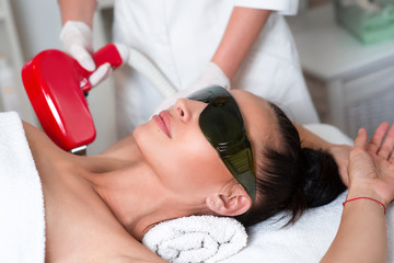 Beautiful woman face on armpits laser hair removal at epilation cabinet