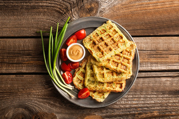 Metal tray with tasty squash waffles and sauce on wooden table