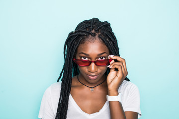 Portrait of excited young african female in sunglasses on blue background