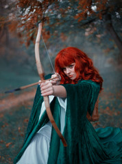 brave red-haired girl holds a bow in her hands, directing an arrow, experienced hunter goes into battle, warlike image of the princess in emerald cloak and white dress, art in cold colors, Gothic fog