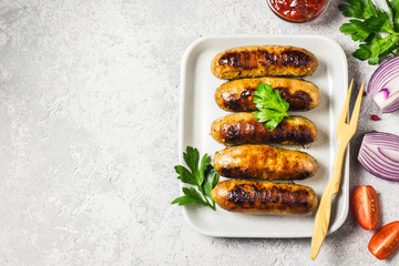 Grilled sausages with sauce vegetables and herbs. Top view, space for text.