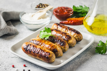 Grilled sausages with sauce vegetables and herbs. Selective focus, space for text.