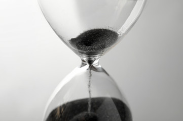Crystal hourglass with falling sand on grey background. Deadline concept