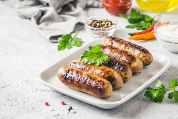 Grilled sausages with sauce vegetables and herbs. Selective focus, space for text.