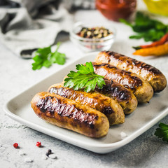 Grilled sausages with sauce vegetables and herbs. Selective focus, space for text.