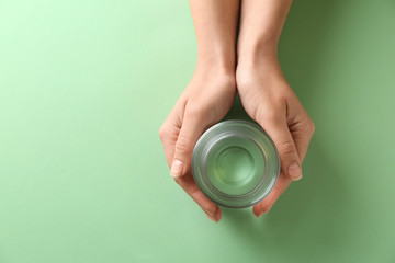 Female hands with glass of fresh water on color background
