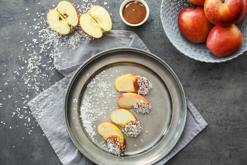 Metal tray with candy apple wedges and sauce in bowl on grey table